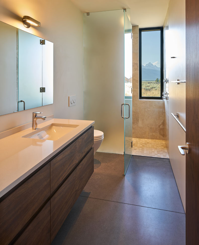 In this modern bathroom, there's a tall window in the shower, while a floor-to-ceiling frosted glass shower screen and door keeps the rest of the bathroom dry. #BathroomDesign #FrostedShowScreen #Window