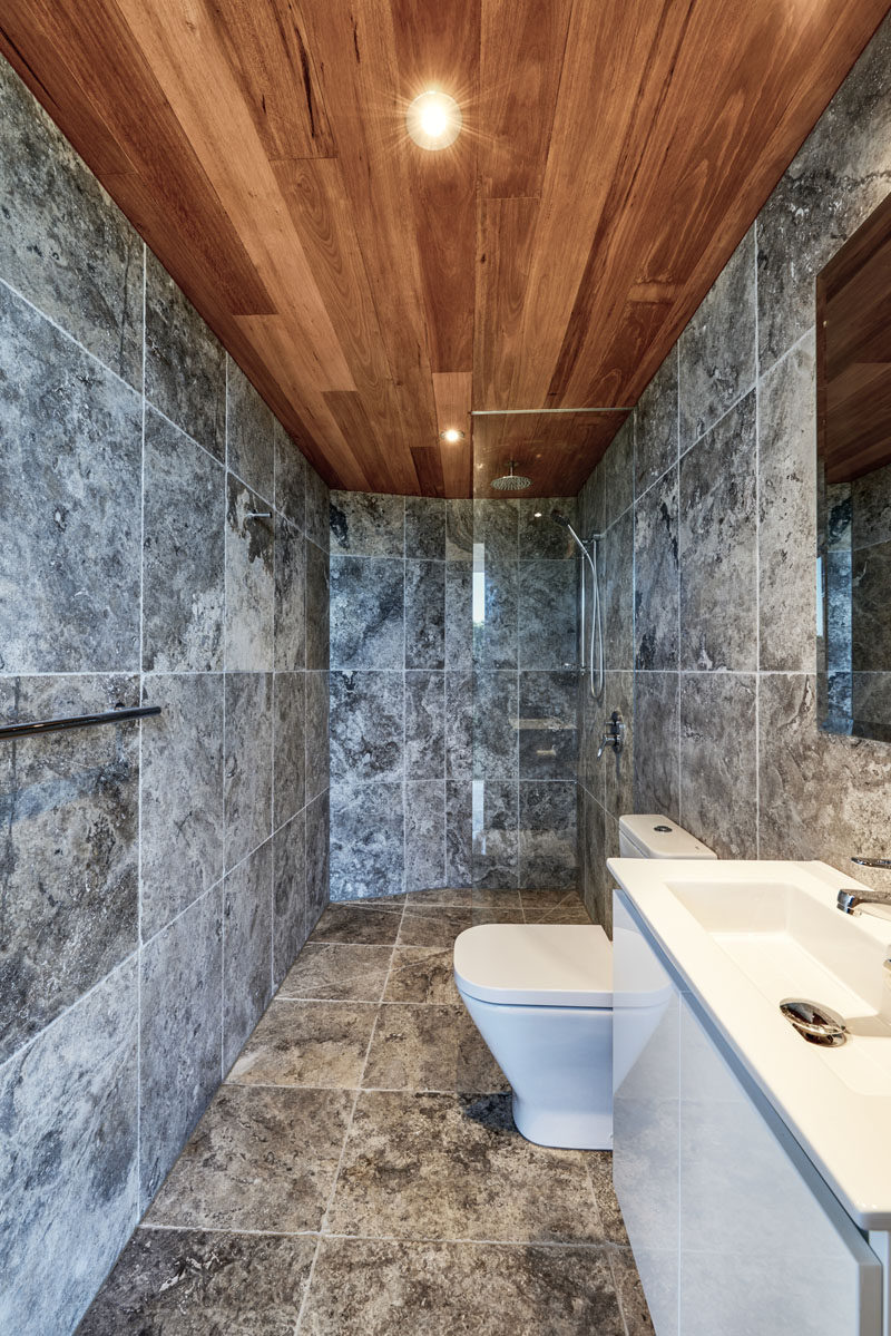 This modern bathroom with grey tiles and a walk-in shower with glass shower screen, is located within a pool cabana. #Bathroom #ModernBathroom