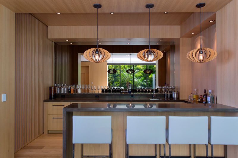 This modern home bar has a mirrored backsplash to make the room feel larger. #MirroredBacksplash #HomeBar