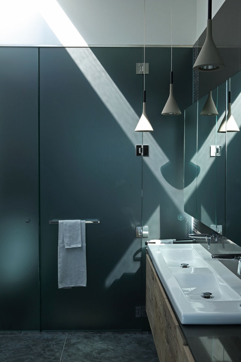 In this modern ensuite bathroom, the shower and toilet is hidden from view by frosted dark glass. #BathroomDesign #ModernBathroom