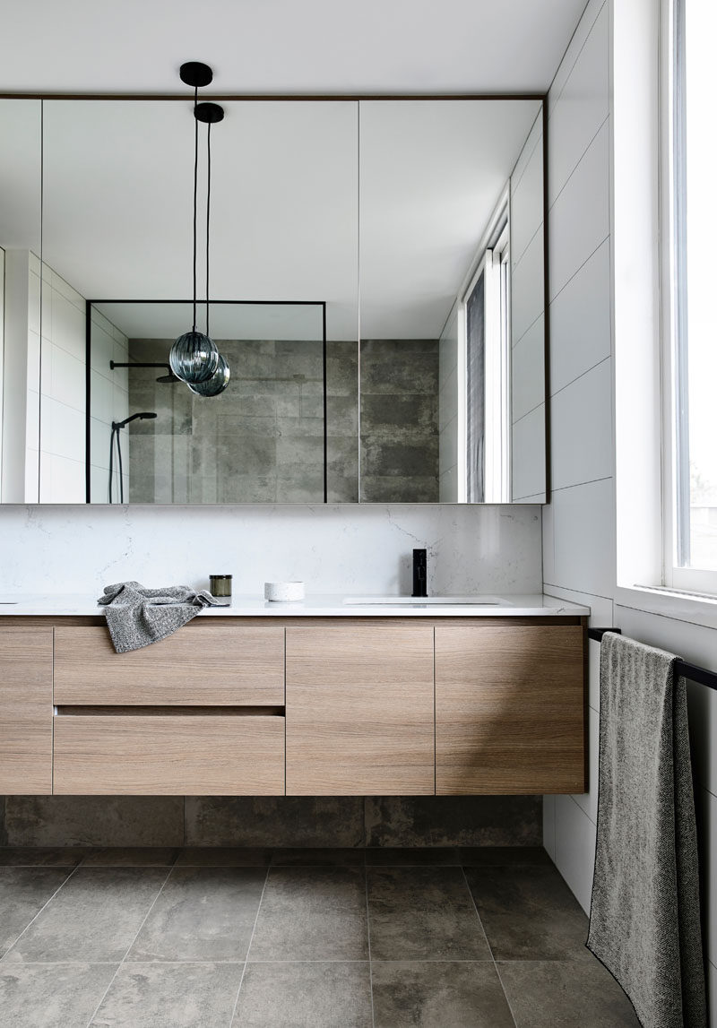 In this modern bathroom, stone tile has been used for the flooring and as an accent wall in the shower. #BathroomDesign #ModernBathroom