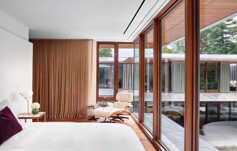 This modern guest bedroom features floor-to-ceiling windows that provide a view of the top floor of the main house and the pool below. #GuestBedroom #Windows