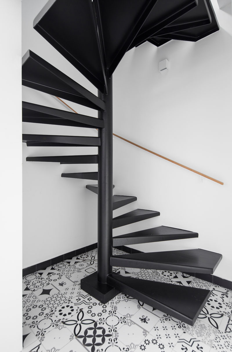 This modern two-floor apartment has black steel spiral stairs connect the different levels. #ModernStairs #BlackSpiralStairs