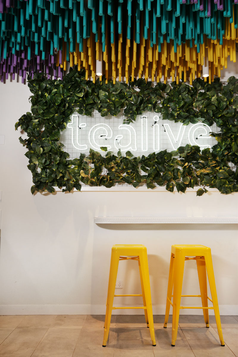 FRETARD Design have completed a bubble tea store that features a colorful dowel accent ceiling and a partial green wall around a neon light. #InteriorDesign #RetailDesign