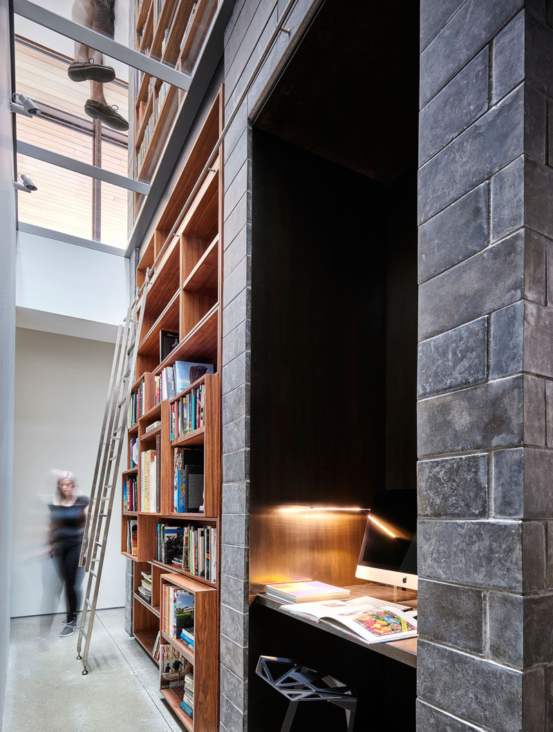 This modern house has a library with a built-in wood bookshelf, and an alcove with a desk and computer. #Bookshelf #BuiltInBookshelf