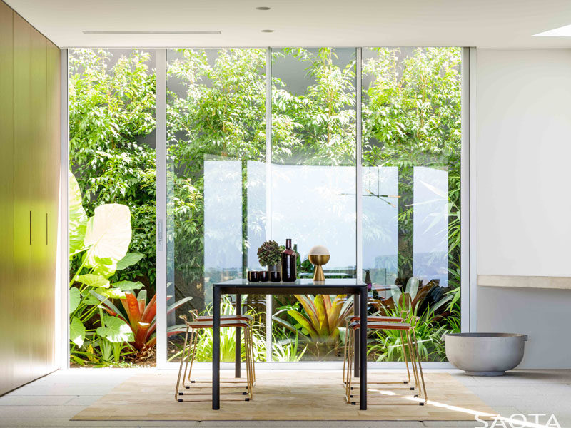 Floor-to-ceiling windows show off the landscaped garden in this dining room. #Windows #Landscaping