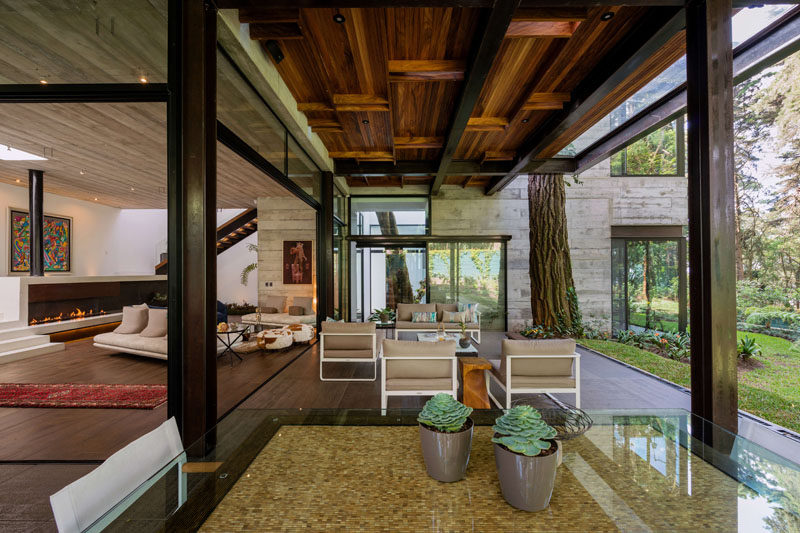 This modern house has a covered patio with a wood ceiling, that's home to an outdoor lounge and dining area. #ModernPatio #OutdoorSpace