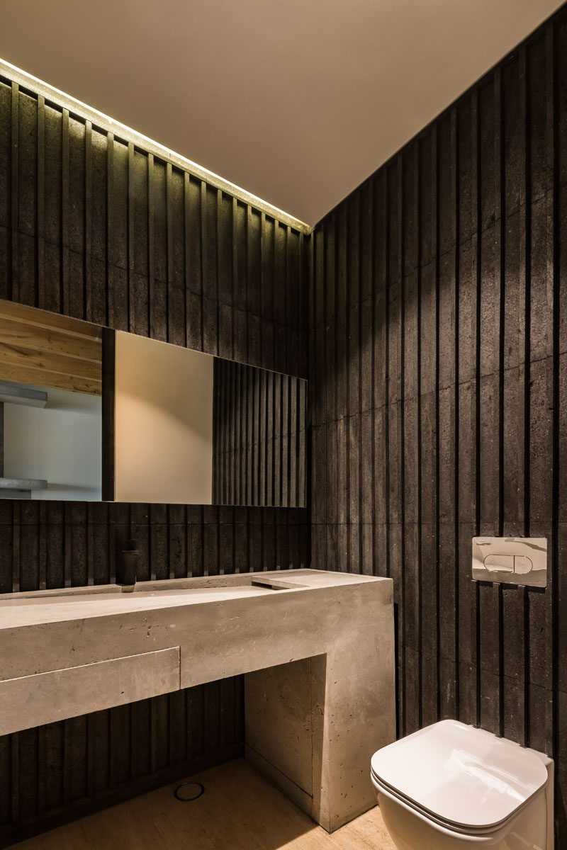 In this modern bathroom, wood detailing has been darkened, creating a strong contrast to the concrete vanity and the white ceiling. #DarkWood #ModernBathroom #ConcreteVanity