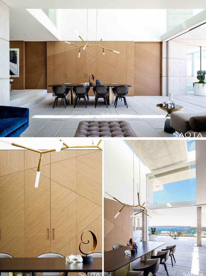 This modern dining area has a double height ceiling, while a hidden door, built into the wood accent wall, reveals the kitchen. #DiningRoom #DoubleHeightCeiling