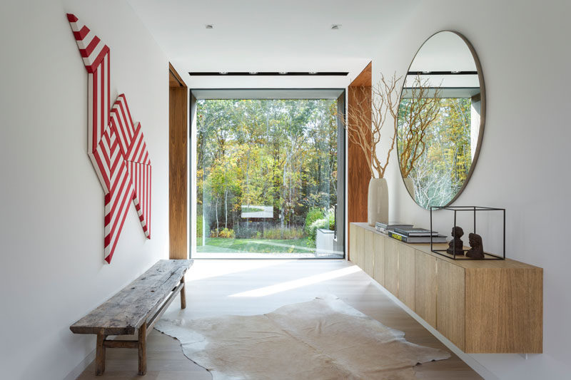 Stepping inside this modern house, the entryway has a large window that perfectly frames the trees outside. #ModernEntryway #Windows