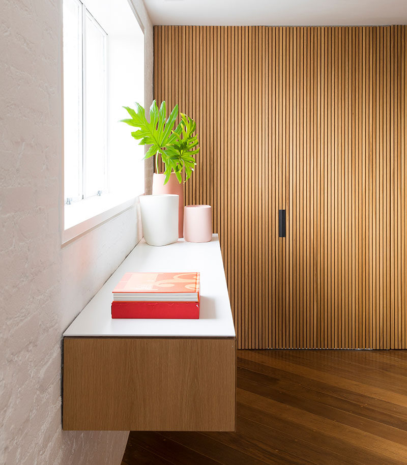 The door to the kitchen is hidden within a wood accent wall in this modern apartment. #HiddenDoor #WoodAccentWall #ModernApartment