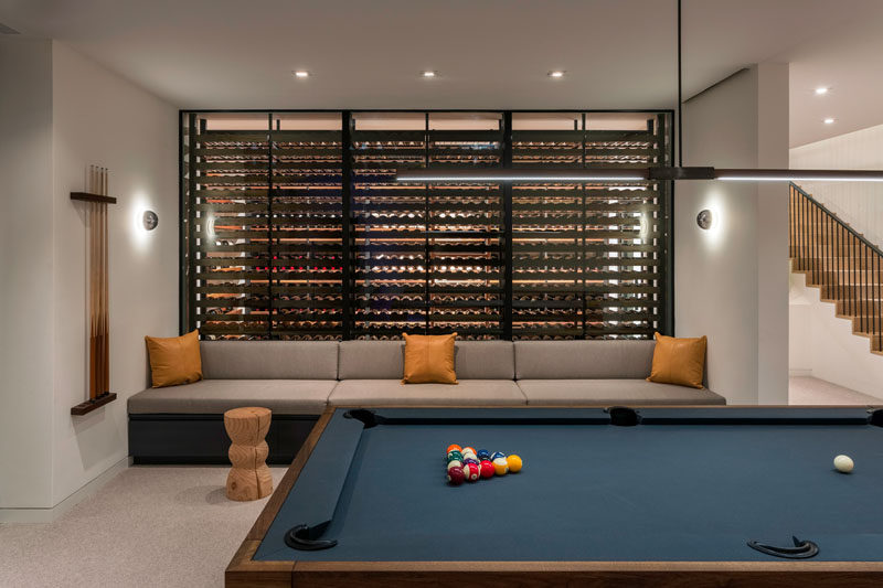 This modern house has a wine room with blackened steel supports and custom walnut shelving, and is used as a back drop to a custom banquette in the game room. #WineRoom #WineCellar #GamesRoom #BanquetteSeating