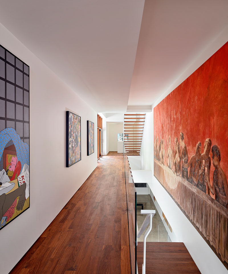 The white hallways and walls throughout this modern house are filled with art pieces. #ModernHouse #WoodFlooring #Hallways