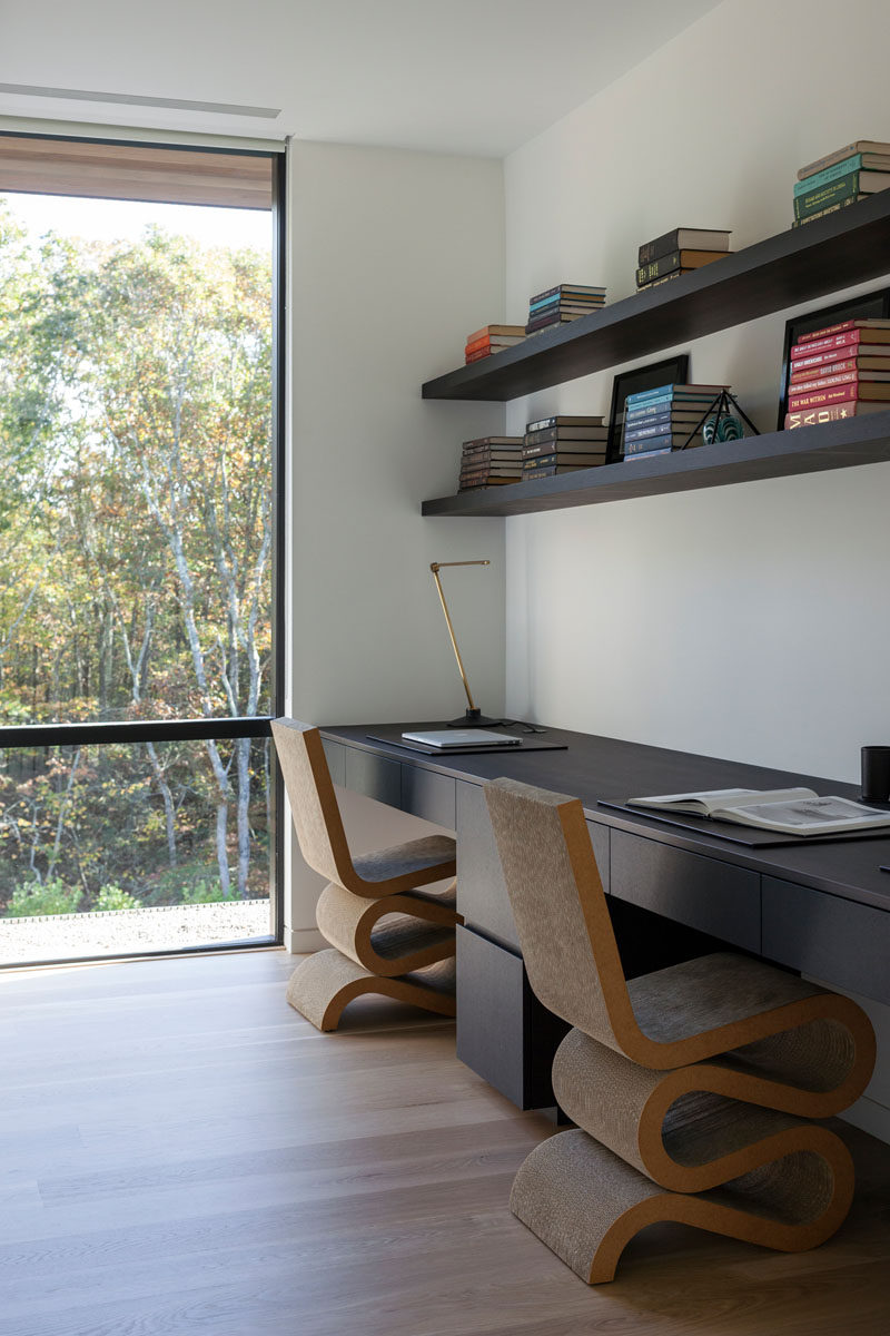 This modern home office features a built-in desk with enough room for two people, and shelving above that acts as a bookshelf. #HomeOffice #ModernHomeOffice