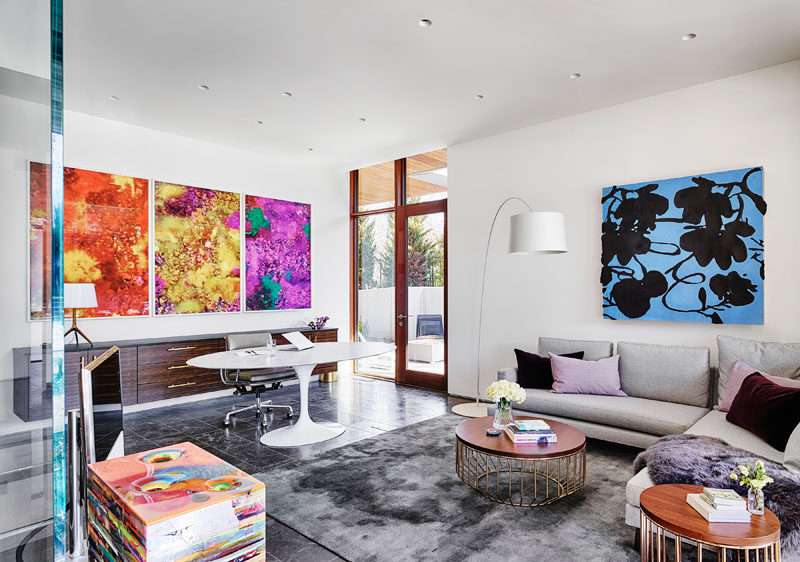 In this modern home office, there's a large sideboard that sits below colorful artwork, while a couch provides a comfortable place to relax. #ModernHomeOffice #HomeOffice