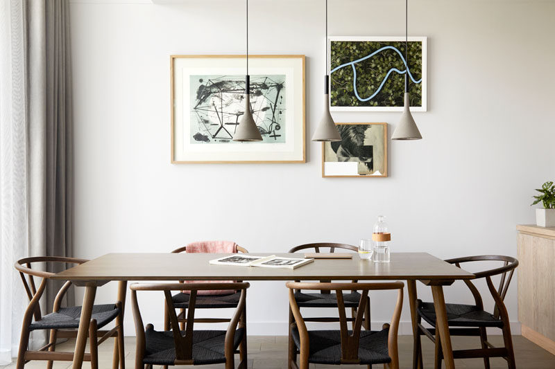 Three simple pendant lights hang above a wood dining table in this modern hotel apartment. #ModernDiningRoom #HotelRoom