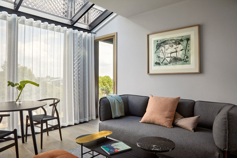 This modern hotel apartment has a simple living room with floor-to-ceiling windows and a skylight. #ModernLivingRoom #HotelRoom