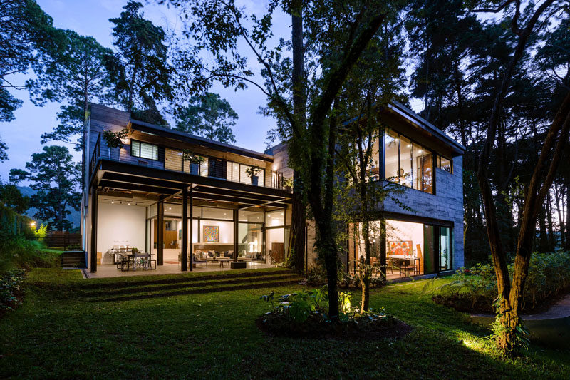 All the trees on the site of this modern house were kept and integrated in the design. In the backyard, the tall trees are highlighted are night. #ModernHouse #Trees #Landscaping