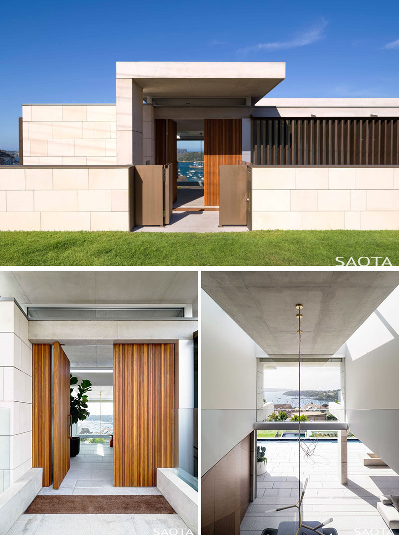 Entering the home through a pivoting wood front door, visitors step into a dramatic entrance that's emphasized by a double volume entrance space with open views right through the house to Sydney Harbour and beyond. #ModernHouse #WoodFrontDoor #PivotingFrontDoor #DoubleHeightCeiling