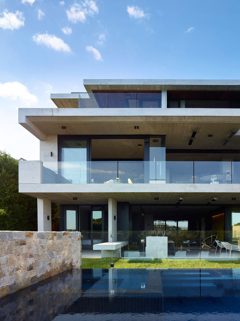 The lowest level of this modern house opens up to a covered patio area and the backyard that features a swimming pool. #ModernHouse #SwimmingPool #Patio