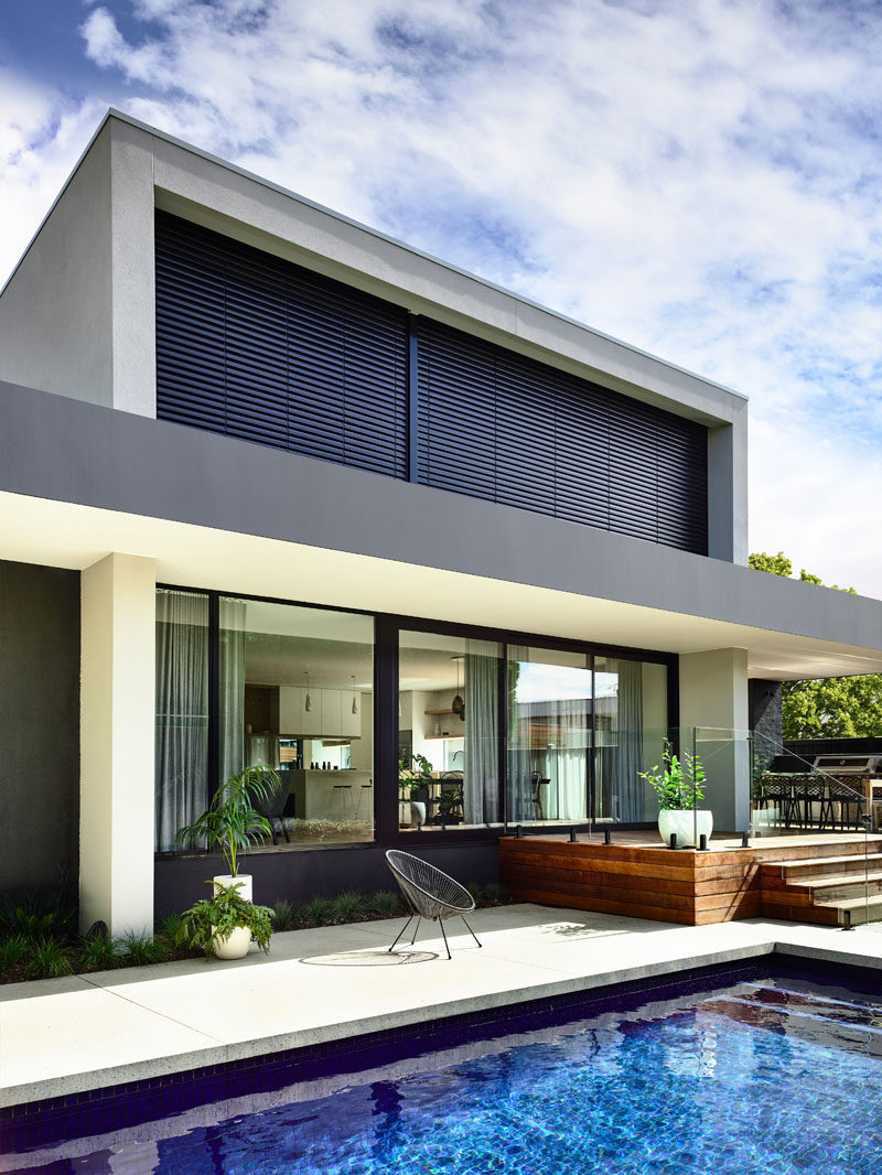 Accessed from the main social areas of this modern house, the backyard features a raised deck that overlooks the cobalt blue pool. #Deck #ModernHouse #Backyard #SwimmingPool