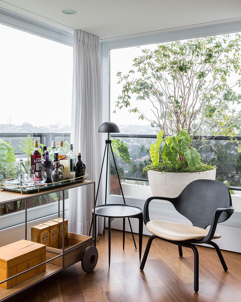 This sun room with large window on three sides, has been furnished with a small seating area and a bar cart. #Sunroom #Windows #InteriorDesign