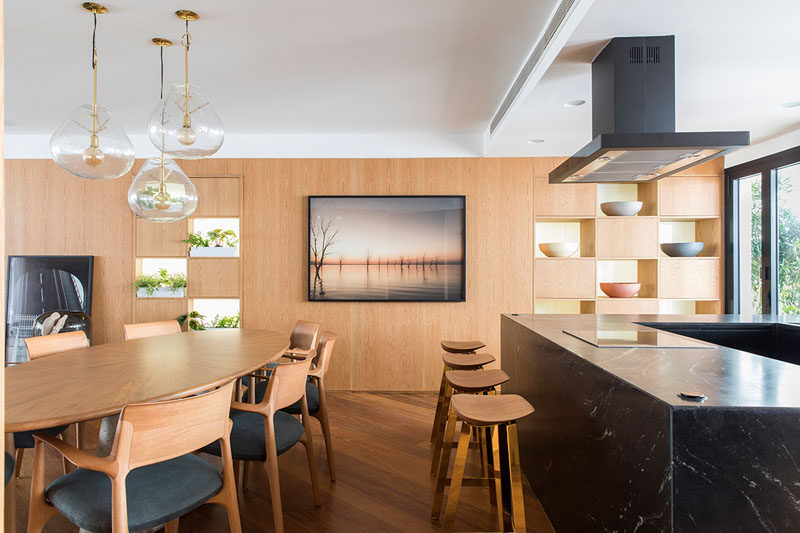 In this modern apartment, a wood accent wall with open sections for plants and displays runs the width of the apartment. #AccentWall #InteriorDesign #WoodWall