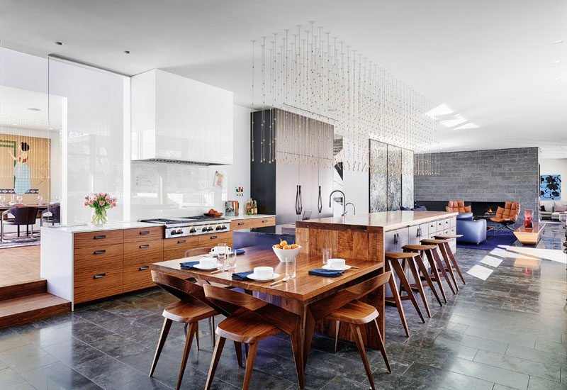 In this modern kitchen, tere's a small casual dining area attached to the end of the kitchen island, while behind the kitchen and on the other side of the hallway, is a formal dining room. #Kitchen #ModernKitchen #KitchenDesign