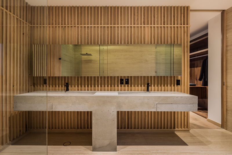 In this modern bathroom, a custom-designed dual sink concrete vanity stands out against the wood walls. #ModernBathroom #ConcreteVanity #BathroomDesign