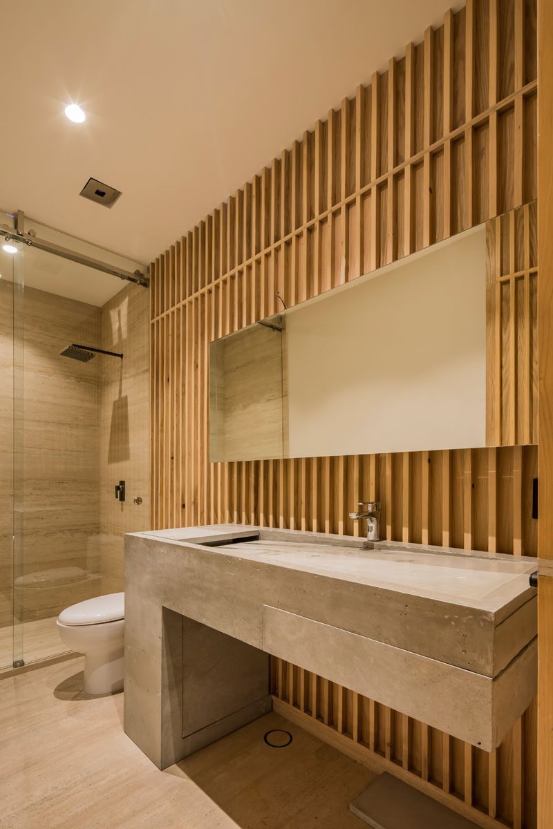 In this modern bathroom, a custom-designed concrete vanity stands out against the wood walls. #ModernBathroom #ConcreteVanity #BathroomDesign