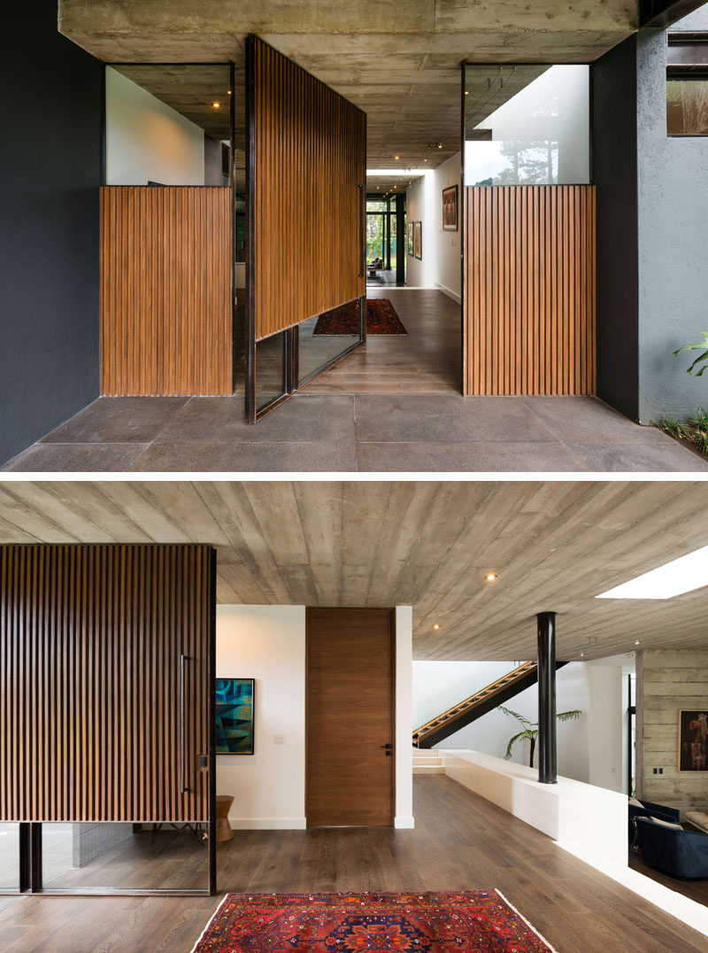 A large pivoting wood and glass front door welcomes people to this modern house. #FrontDoor #ModernFrontDoor #PivotingWoodFrontDoor