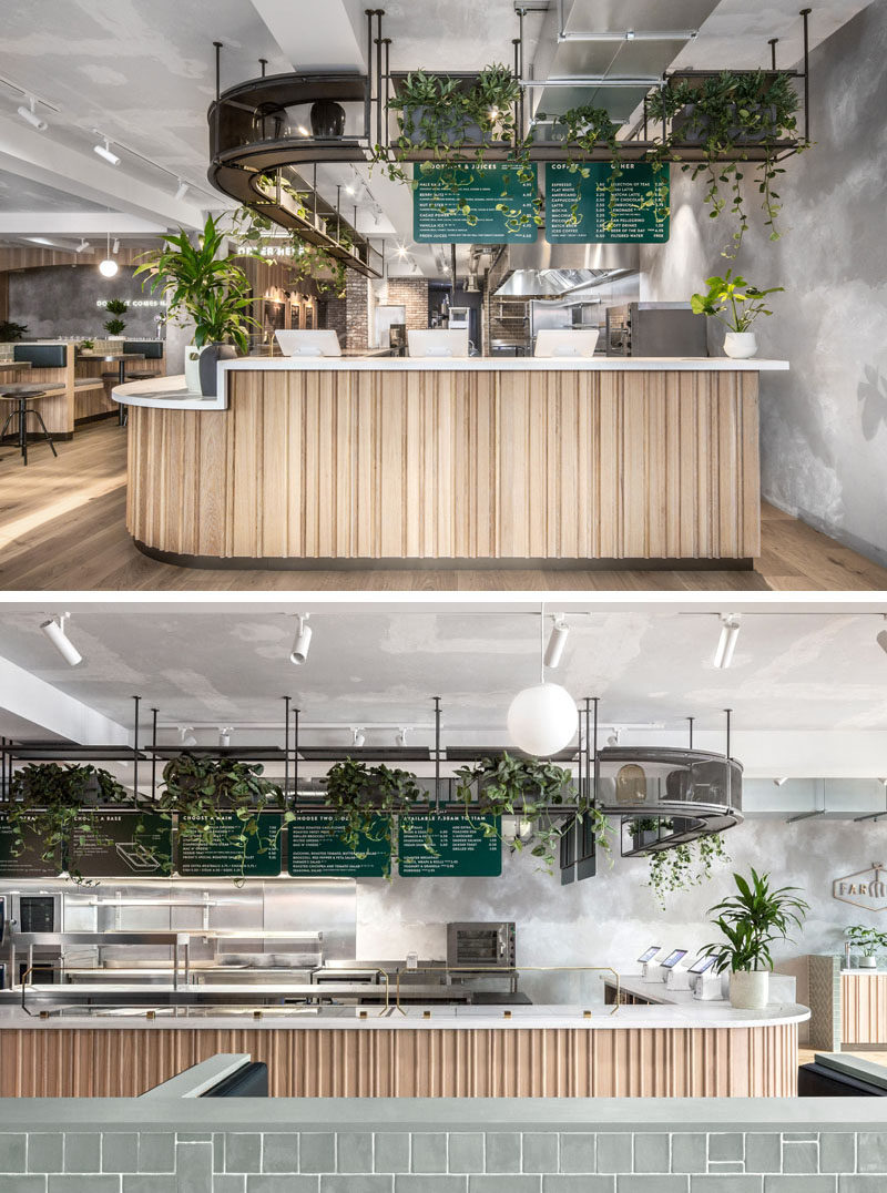 This modern restaurant features a service area with a wood facade, a white countertop, and rendered concrete walls. #RestaurantDesign #RestaurantInterior