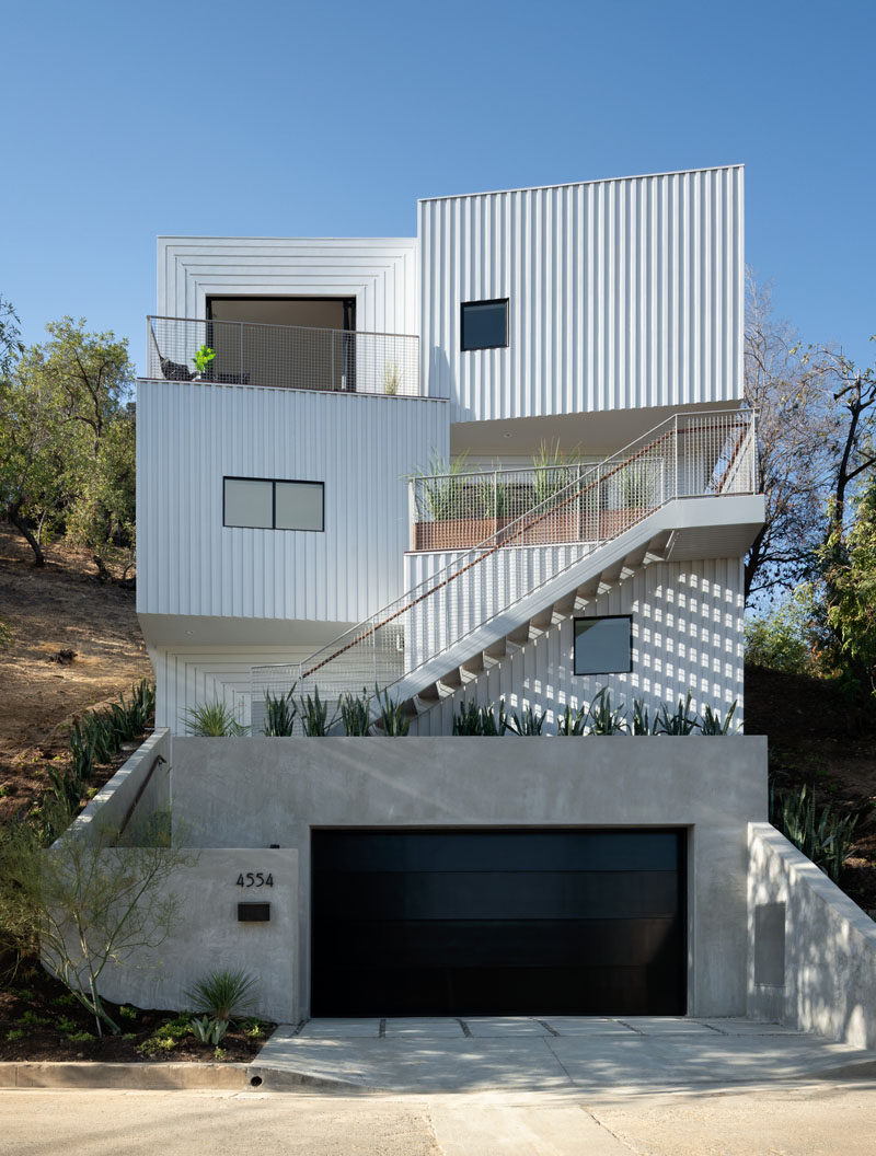 The exterior cladding of this modern house has been custom-made, with its design being a play on board-and-batten siding and organized into patterns that suggest varied depth and texture. #ModernHouse #Siding #ModernArchitecture