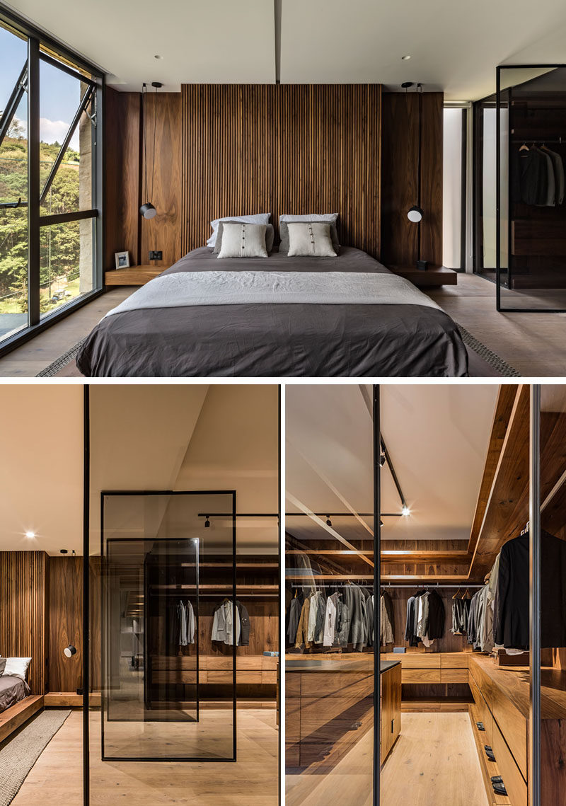 In this modern master bedroom, a rich wood accent wall becomes the backdrop for the bed, while beside the bed, a wall of pivoting glass doors reveal the walk-in closet and dressing room. #MasterBedroom #ModernBedroom #BedroomDesign #Closet #WalkInCloset #DressingRoom