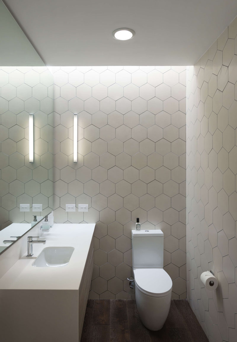 In this modern bathroom, white hexagon tiles cover the walls helping to keep the room bright. #ModernBathroom #WhiteHexagonTiles