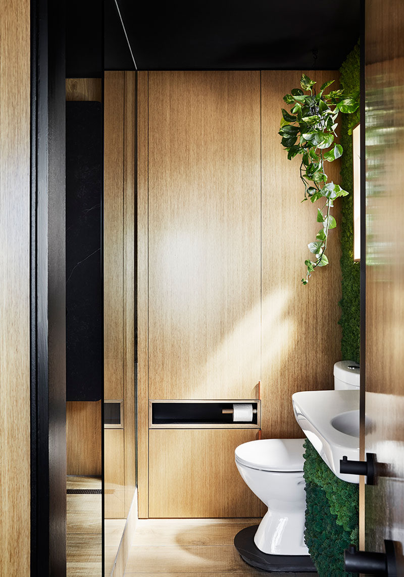 This small and modern bathroom features timber-look porcelain tiles, a green wall, and a fold-down clothes drying rack. #SmallBathroom #BathroomDesign