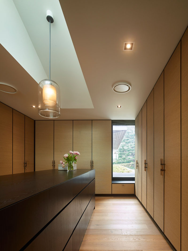 This modern dressing room features floor-to-ceiling cabinets with a central dark wood dresser. #ModernDressingRoom #InteriroDesign