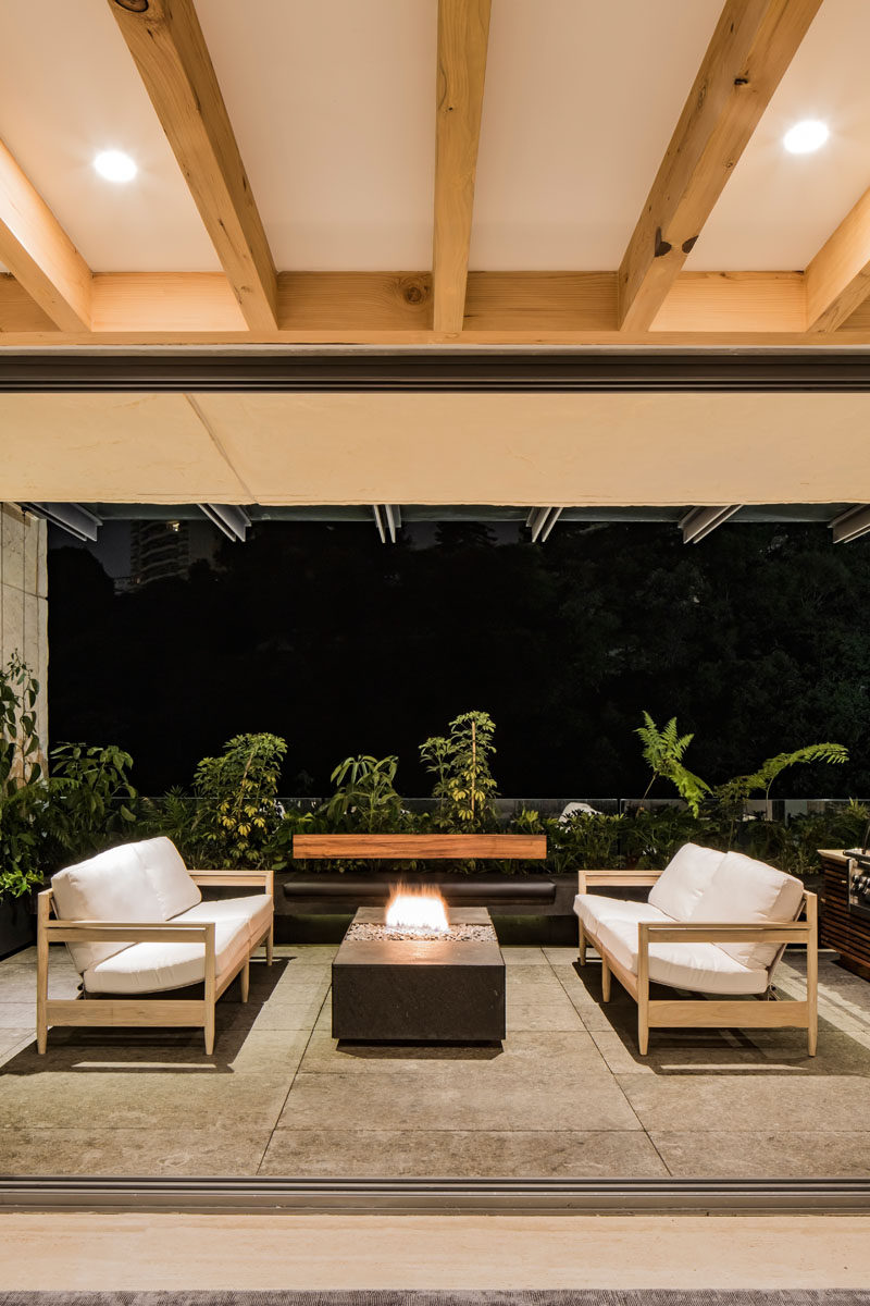 This modern apartment opens to a covered balcony, that has an outdoor sitting area with a tabletop fireplace. #OutdoorSittingArea #Firetable #Balcony