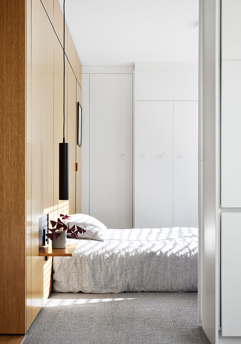 This modern and minimalist bedroom features wood accent wall that becomes the headboard, with a small cut-out revealing a small wall panel that folds down to form the bedside table. #ModernBedroom #WoodAccentWall