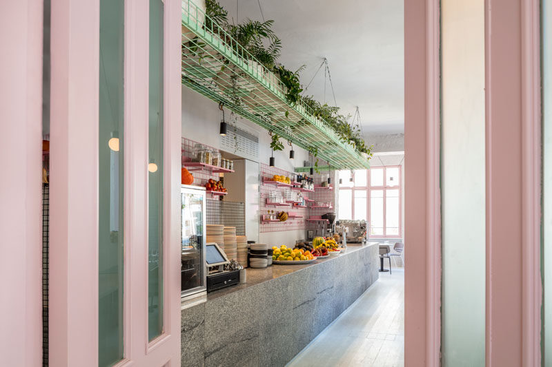 Amit Design Studio has recently completed Bana, an organic food cafe that's located in Tel Aviv, Israel, and has design features like pink metal grid shelving and a large basket filled with plants that hangs from the ceiling. #ModernCafe #CafeDesign #InteriorDesign