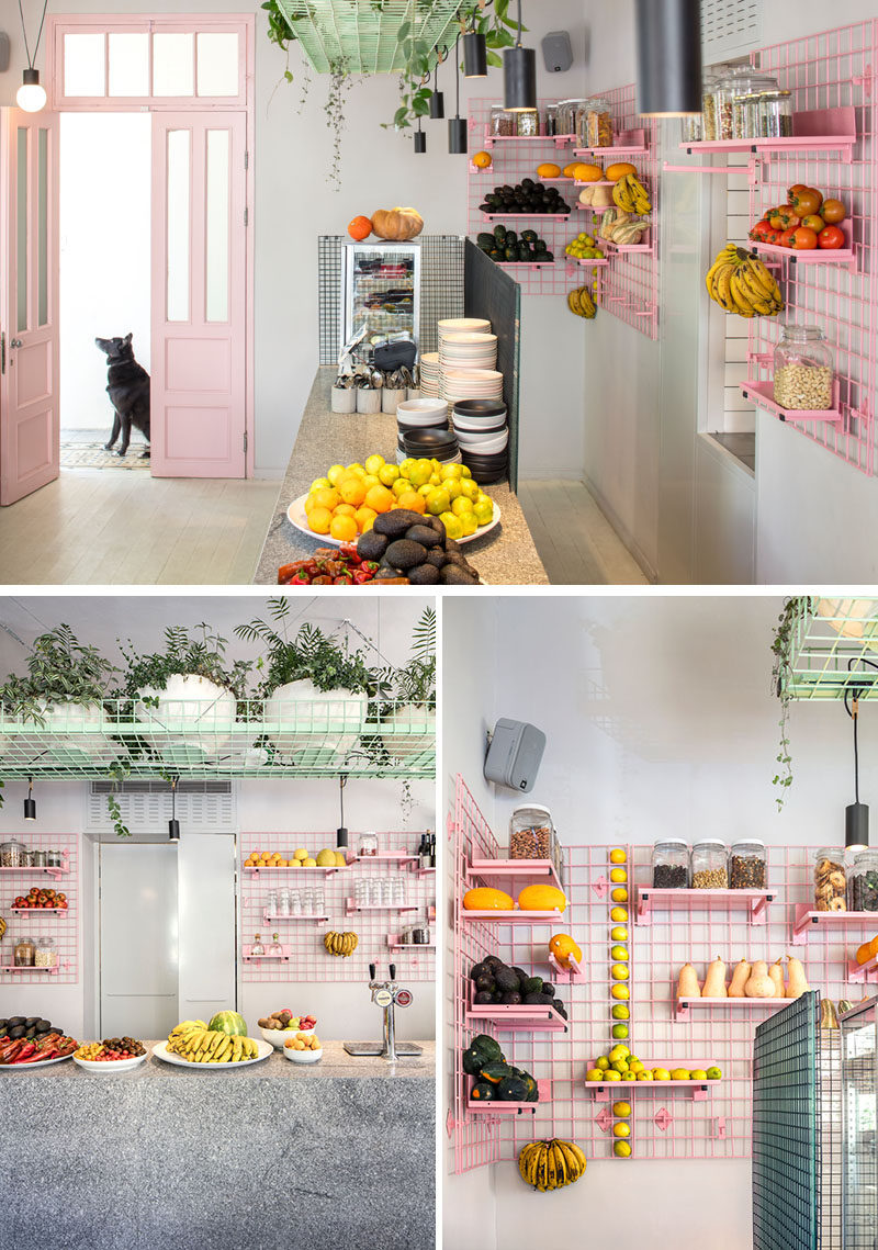 On the wall behind the bar of this modern cafe is a pink metal grid shelving system that allows the shelves to display the fresh fruit and vegetables. Due to the design of the grid unit, the shelves and hooks can be easily moved, depending on the requirements of the day. #Shelving #GridShelving #PinkShelving