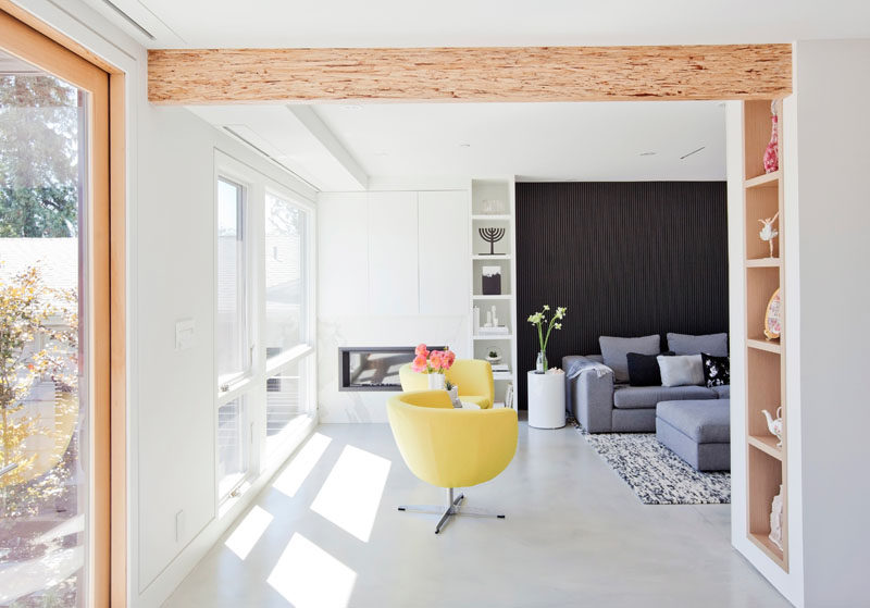 An opening between the living room and the dining room in this modern house, shows off a wood beam, and custom built-in shelving. #WoodShelving #WoodBeam