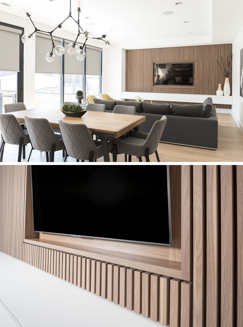 This modern living room features a wood slat accent wall that surrounds the TV and provides a row of white storage cabinets. #TVWall #InteriorDesign #AccentWall #LivingRoom