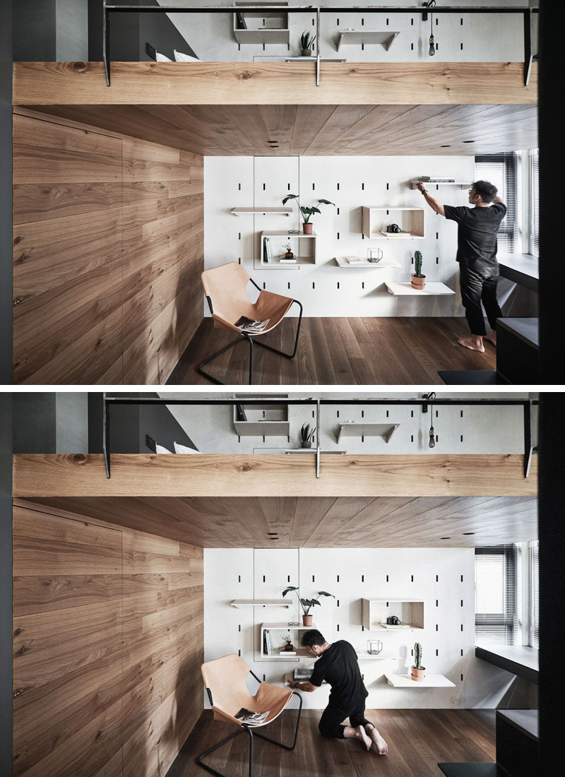 On the lower level of this modern apartment, the space is dedicated to a home office, that features a pegboard wall and allows the shelving to be moved when needed. The wood accent wall hides the door to the bathroom. #ModernApartment #HomeOffice #PegboardWall