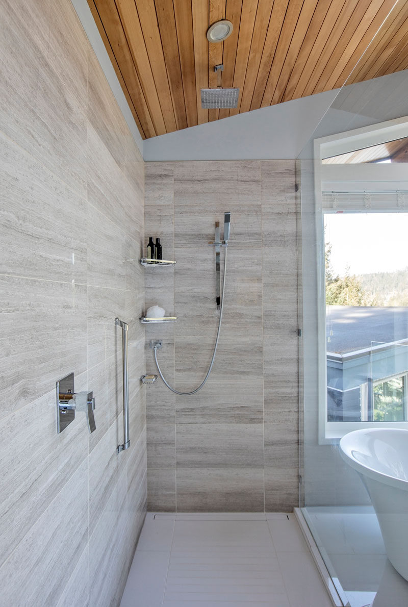 A glass shower screen separates the shower from the bath area in this modern bathroom, and in the shower there's both a rain shower head and a wall mounted one. #Shower #ModernShower