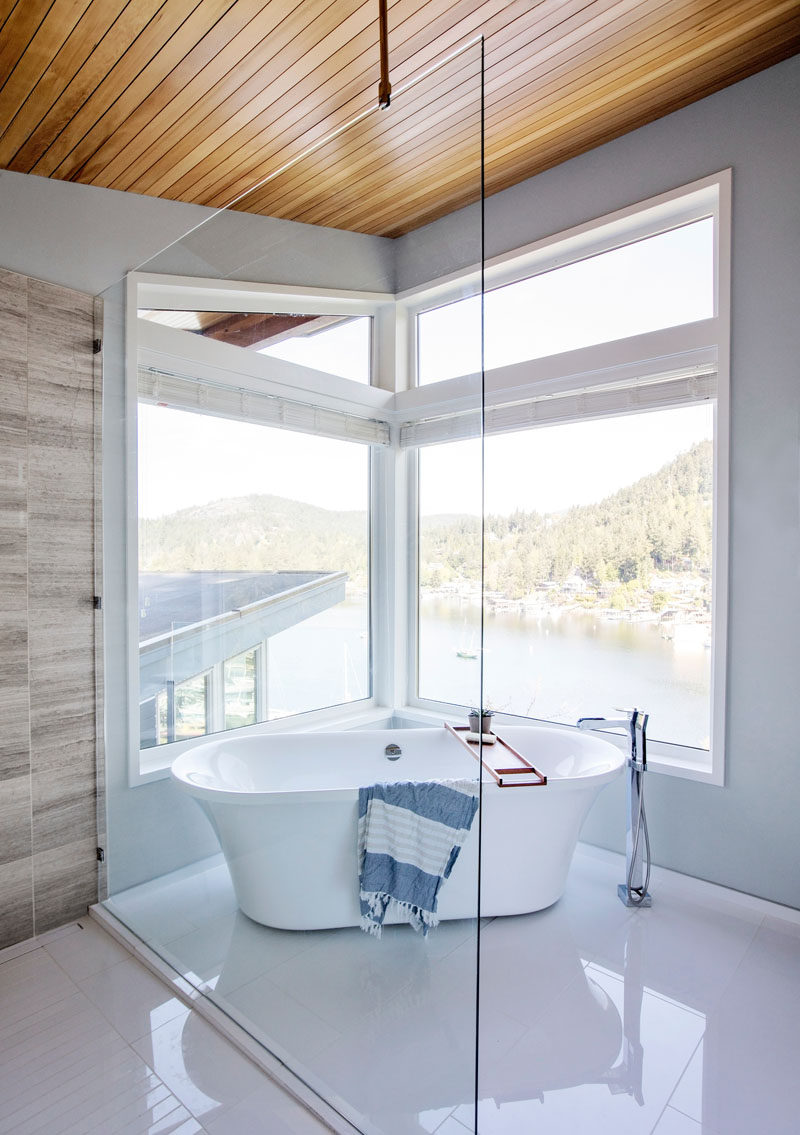 In this modern master bathroom, a freestanding bathtub is positioned below the windows to take advantage of the views. #BathroomDesign #Windows