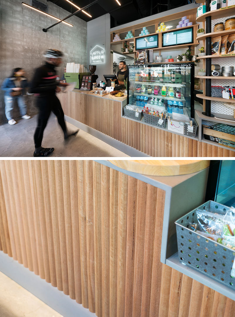 The service counter has a textured wood facade that complements the other wood elements in this modern cafe, and the counter drops down to a different height to display product and create visual interest. #CafeDesign #InteriorDesign #ServiceCounter