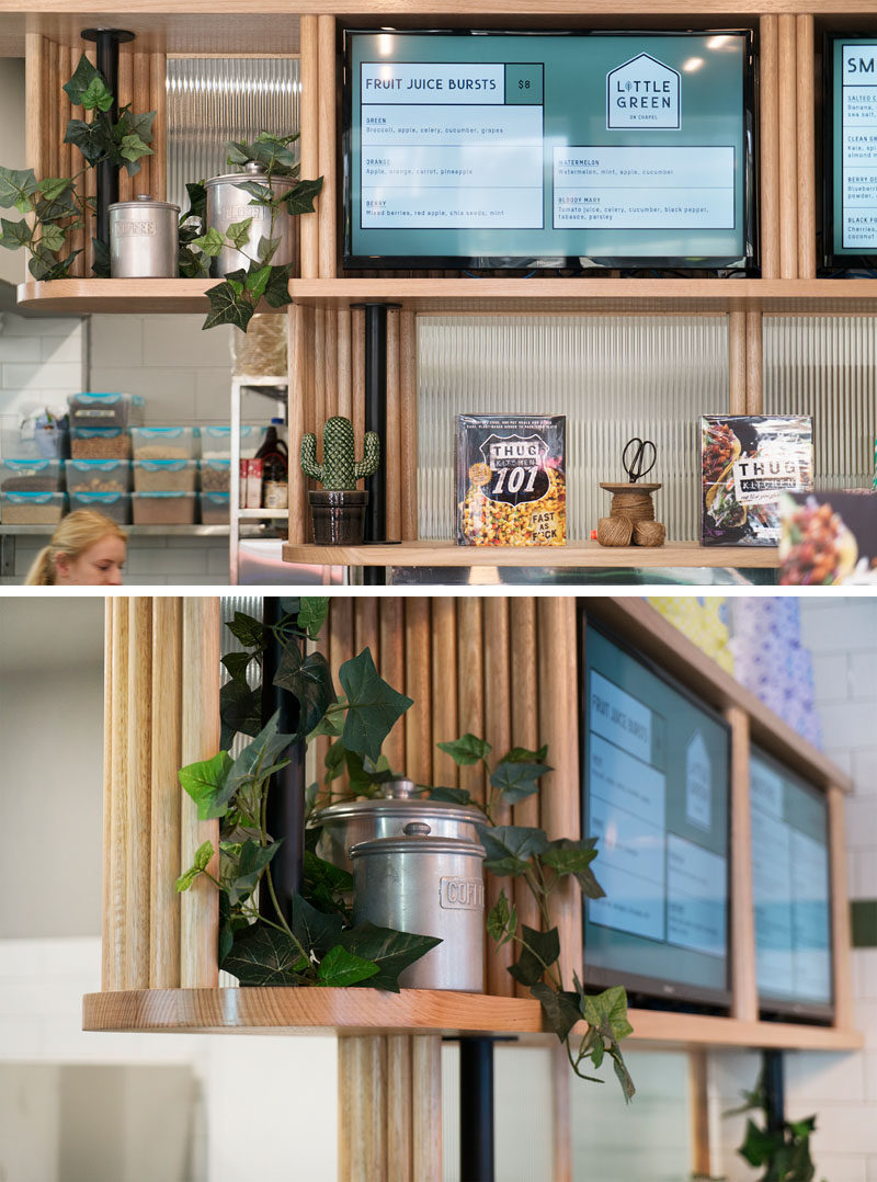 Custom designed wood shelving provides a place for displaying plants, products, and menu boards, in this small and modern cafe. #Shelving #CafeDesign #WoodShelving