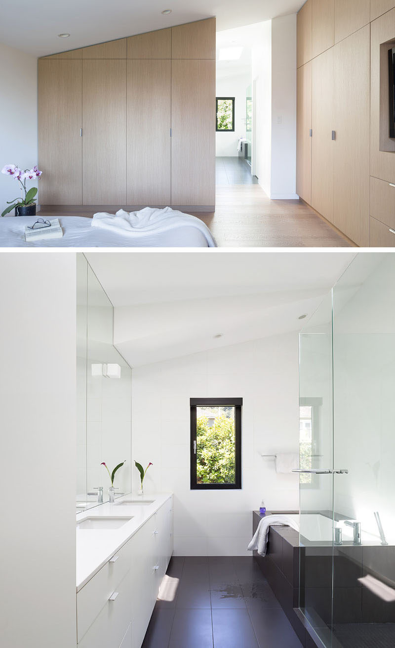 In this modern master suite, minimalist light wood cabinets line the walls, while natural light from the bathroom with a built-in bathtub flows through to the bedroom. #ModernMasterSuite #ModernBathroom #ModernBedroomClosets #BuiltInBathtub