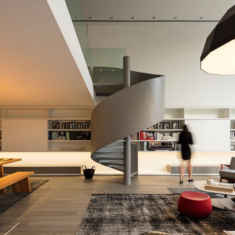 This modern house has grey spiral stairs that lead up to a mezzanine. #SpiralStairs #Stairs #GreyStairs